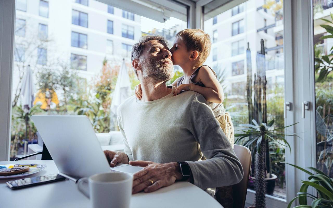 Mann mit Sohn arbeitet im Homeoffice
