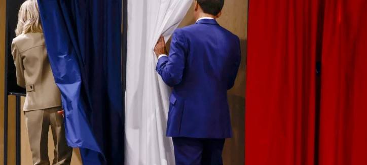 Emmanuel Macron und seine Frau Brigitte betreten während der ersten Wahlrunde eine Wahlkabine.