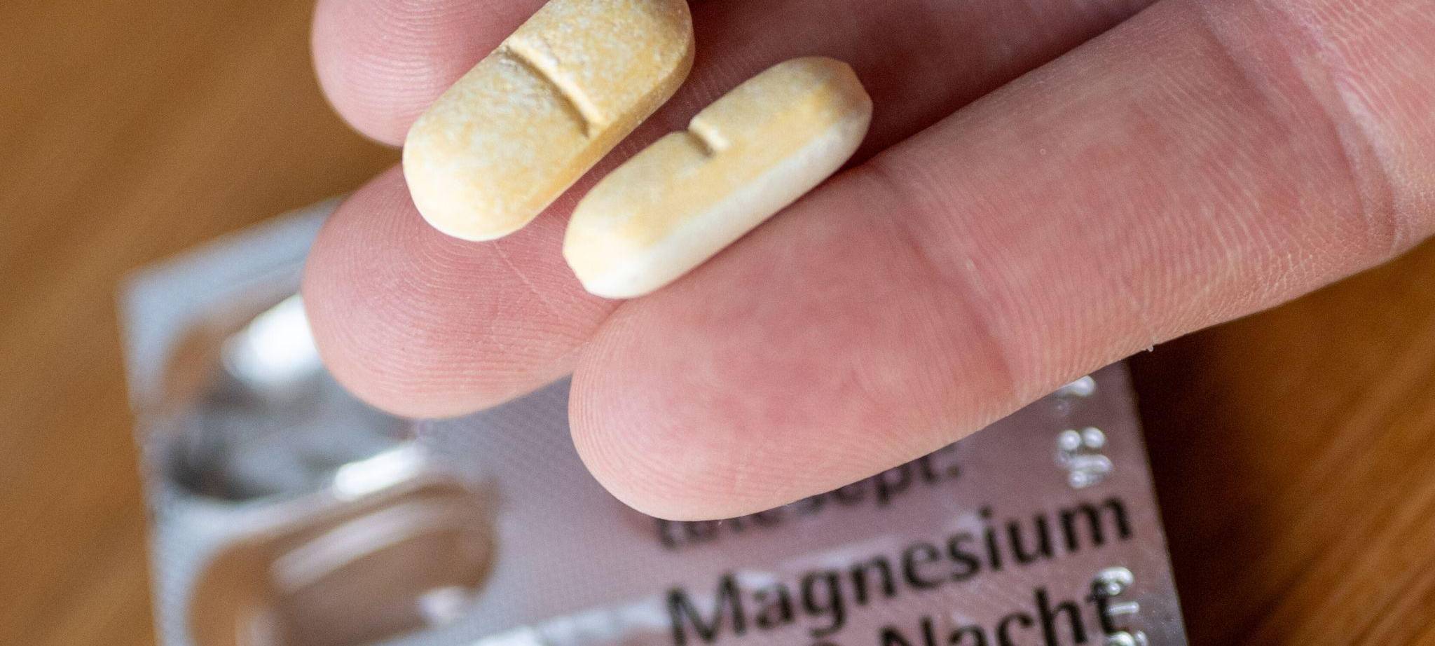 Ein Mann hält zwei Magnesium-Tabletten auf der Hand