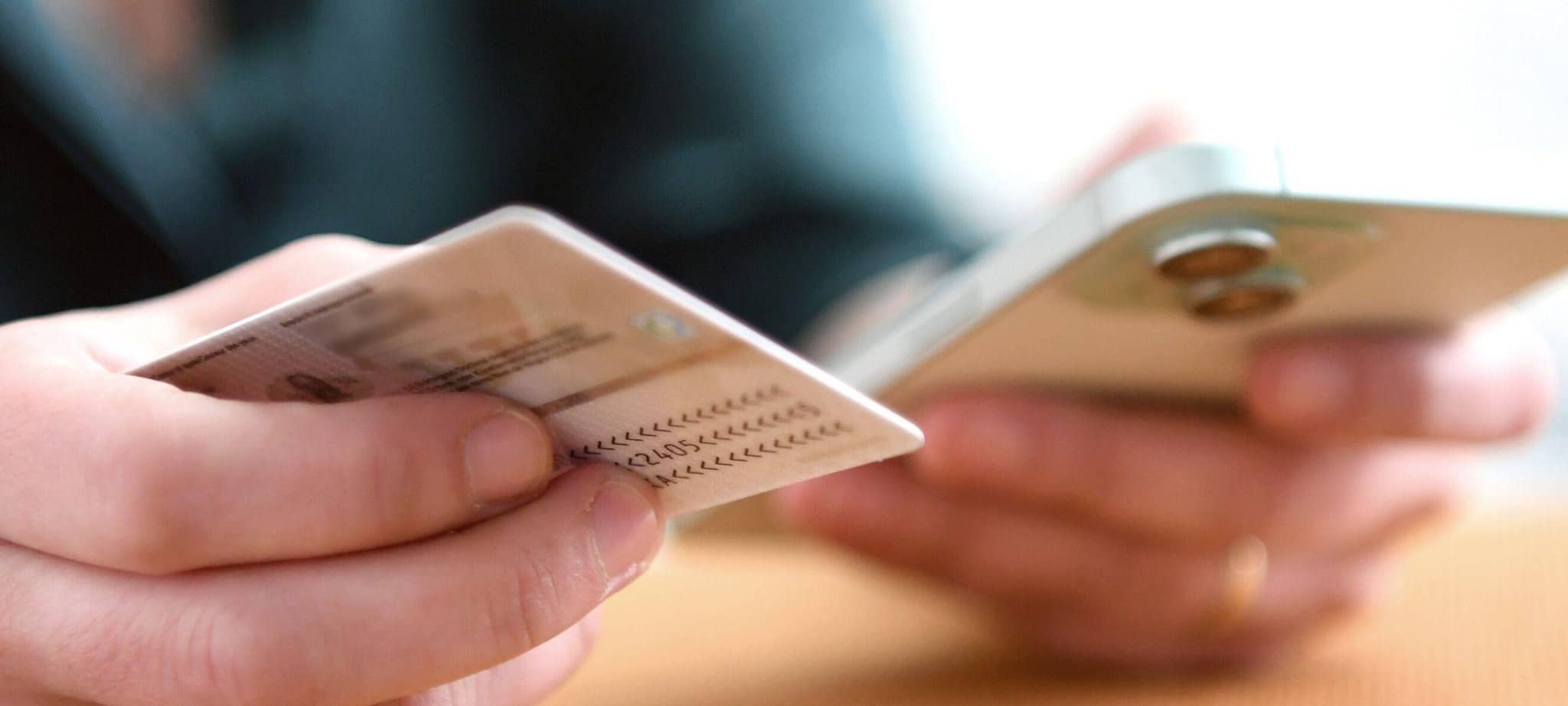 Eine Frau hält Personalausweis und Smartphone in den Händen