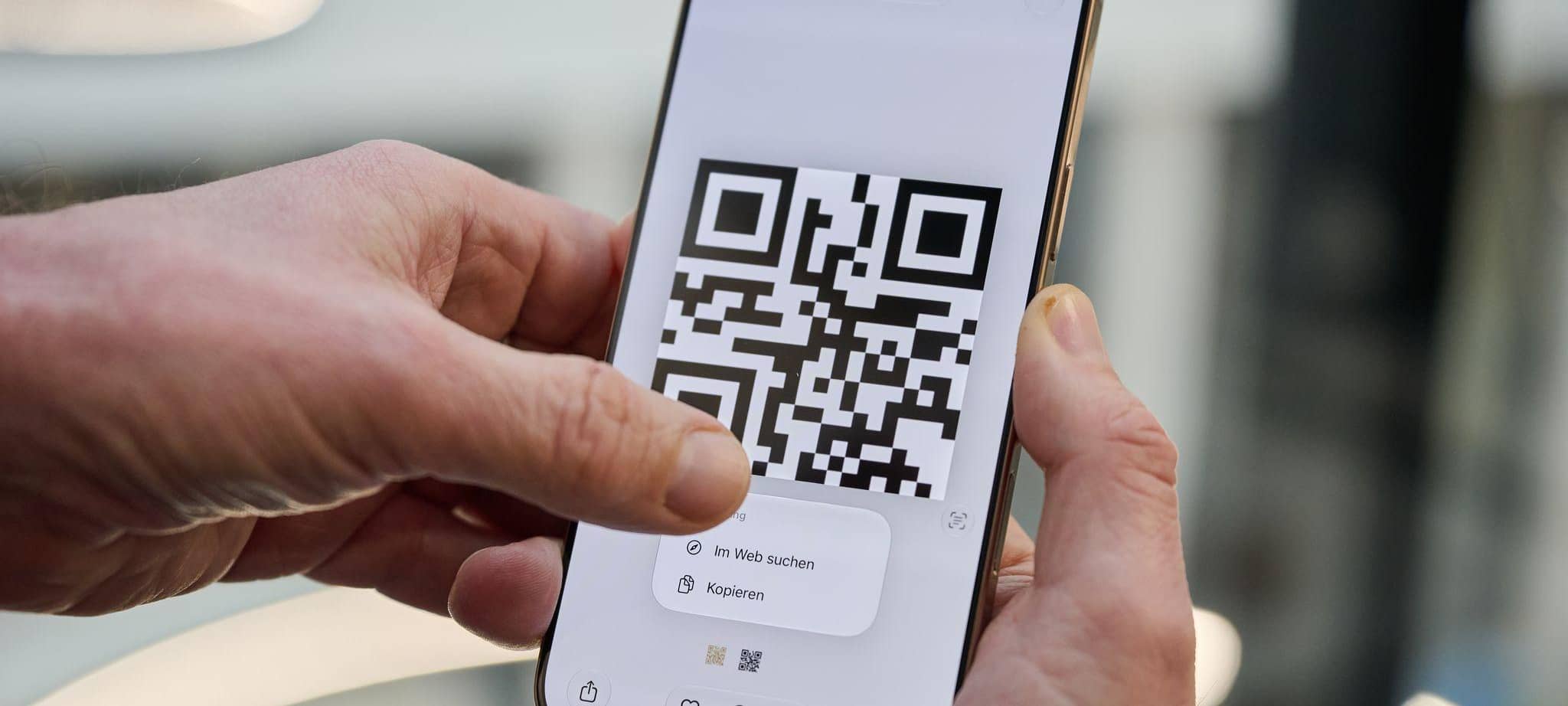 Ein Mann drückt auf einen QR-Code auf einem iPhone